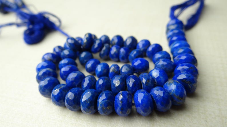 Pu&ograve; includere: Una collana di perline sfaccettate di lapislazzuli blu intenso. Le perline ovali sono infilate insieme, con un nappa blu scuro a ciascuna estremit&agrave;. Le perline hanno una superficie lucida e sono disposte a spirale.