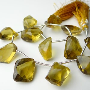 May include: Strand of faceted, golden-yellow gemstone beads with a silver wire string. The beads have irregular shapes and are strung together. A tassel of golden threads is attached to the end.