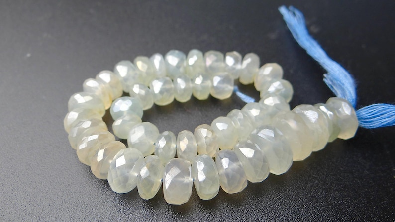 K&ouml;nnte beinhalten: Eine Kette aus facettierten, hellgelb-gr&uuml;nen Edelsteinperlen. Die Perlen sind mit einem blauen Faden aufgef&auml;delt und bilden eine Komponente f&uuml;r eine Halskette oder ein Armband. Die Perlen haben eine durchscheinende Qualit&auml;t und eine polierte Oberfl&auml;che.