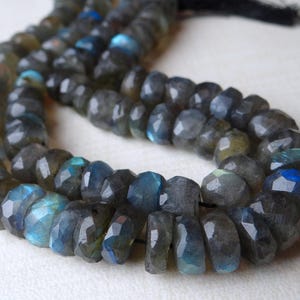May include: Strands of faceted labradorite beads. The beads are primarily gray with flashes of blue and teal. The beads are strung together, creating a necklace or bracelet.