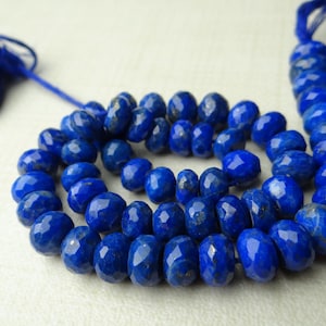 Pu&ograve; includere: Una collana di perline sfaccettate di lapislazzuli blu intenso. Le perline sono disposte a spirale, con un nappa di filo blu a ciascuna estremit&agrave;. Le perline hanno una superficie lucida e riflettente.