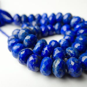 Pu&ograve; includere: Una collana di perline di lapislazzuli blu intenso sfaccettate. Le perline sono di un blu ricco e saturo con una superficie lucida e riflettente. Le perline sono infilate con un cordoncino blu abbinato, creando una collana di pietre preziose.