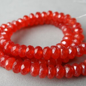 May include: Strands of faceted, vibrant red gemstone beads. The beads are strung together, forming a necklace or bracelet. The beads have a sparkling, polished appearance, and are displayed against a neutral background.
