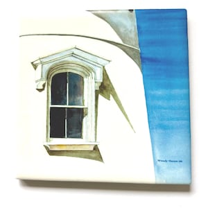 Puede incluir: Impresión artística en lienzo cuadrado que presenta una pintura a la acuarela de un edificio blanco con una ventana. La ventana tiene un marco decorativo. Una sección azul está en el lado derecho. El nombre y el año del artista están impresos en la parte inferior derecha.