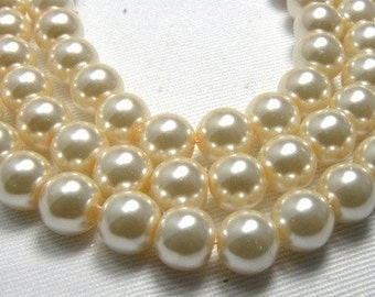 May include: A multi-strand necklace featuring round, cream-colored pearls with a smooth, lustrous finish. The pearls are uniform in size and shape, strung together in parallel rows to create a classic, layered appearance with a soft, reflective sheen.