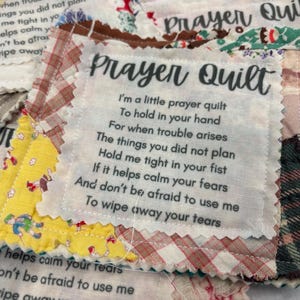 May include: A white fabric square with the text "Prayer Quilt" printed on it. The text reads: "I'm a little prayer quilt to hold in your hand for when trouble arises. The things you did not plan. Hold me tight in your fist. If it helps calm your fears. And don't be afraid to use me. To wipe away your tears."