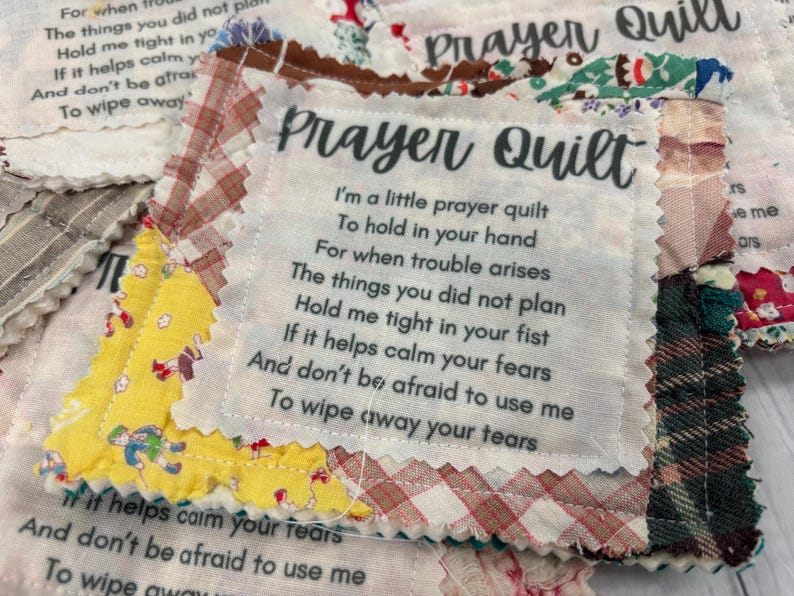 May include: A white fabric square with the text "Prayer Quilt" printed on it. The text reads: "I'm a little prayer quilt to hold in your hand for when trouble arises. The things you did not plan. Hold me tight in your fist. If it helps calm your fears. And don't be afraid to use me. To wipe away your tears."