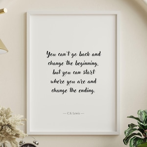 May include: A white framed print with a black and white inspirational quote by C.S. Lewis. The quote reads: "You can't go back and change the beginning, but you can start where you are and change the ending."