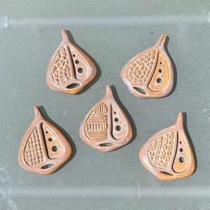 May include: Five ceramic leaf-shaped ornaments with different embossed patterns in shades of brown and beige.