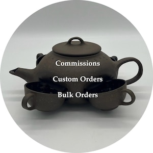 May include: A brown ceramic teapot with a matching lid and two small teacups. The teapot has a curved spout and handle. The text "Commissions", "Custom Orders", and "Bulk Orders" is displayed on the teapot.