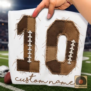 Könnte beinhalten: Ein weißes Sweatshirt mit der Zahl 10 in großen, ausgefransten, braunen Patchwork-Stoffapplikationen mit weißen Schnürdetails im Football-Stil. Unter der Zahl ist der Text custom name in einer braunen Schreibschrift gedruckt.