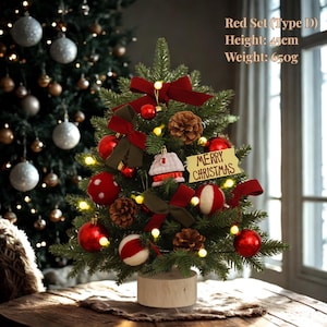 May include: A small Christmas tree decorated with red baubles, bows, and pine cones. The tree, approximately 45cm tall, has a "Merry Christmas" sign and is lit with fairy lights, creating a festive holiday display.