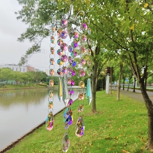 Könnte beinhalten: Ein Kristall-Prisma-Windspiel mit schillernden Regenbogenperlen und tropfenförmigen Kristallen, die an einem Metallrahmen hängen.