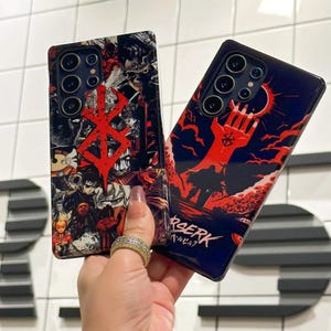 May include: Two black phone cases with a red and black graphic design featuring the Berserk logo and characters. The text "Berserk" is printed on the bottom of one case in Japanese and English.