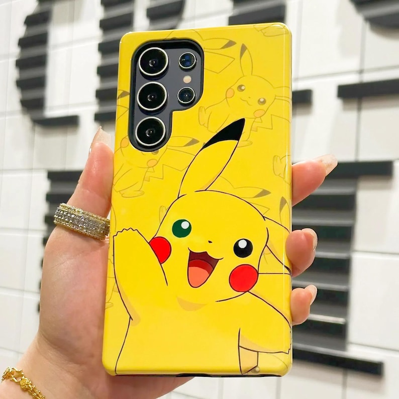 May include: A yellow phone case with a cartoon image of Pikachu, a popular Pokemon character. The case has a black camera cutout and a black border.