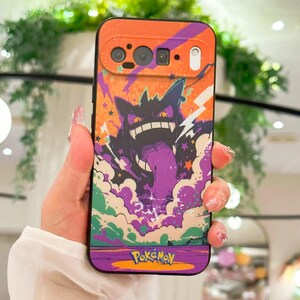 May include: A phone case featuring a purple and black cartoon character with a long tongue, set against a background of orange, purple, and white clouds and lightning bolts. The word "Pokemon" is at the bottom.
