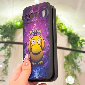 May include: A black phone case featuring a purple background with lightning bolts and a yellow Psyduck character from Pok&eacute;mon. The word "Pok&eacute;mon" is printed above the character. The case has cutouts for the phone's camera and flash.
