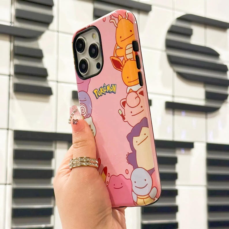 May include: Pink iPhone case with a Pokemon theme. The case features various Pokemon characters, including Pikachu, Bulbasaur, and Charmander. The case also has the word "Pokemon" printed on it.