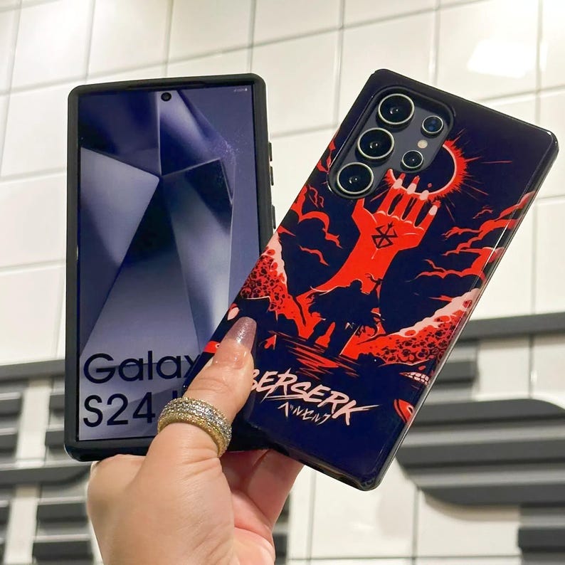 May include: A black phone case with a red and blue graphic of a hand holding a sword. The text "BERSERK" is printed on the case in white letters. The phone case is designed for a Samsung Galaxy S24.