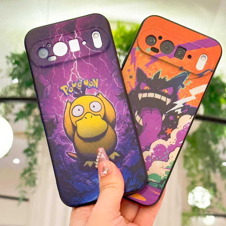 May include: Two phone cases featuring Pok&eacute;mon characters. One case has a purple background with Psyduck, and the other has an orange background with Gengar. Both cases have camera cutouts and the Pok&eacute;mon logo.