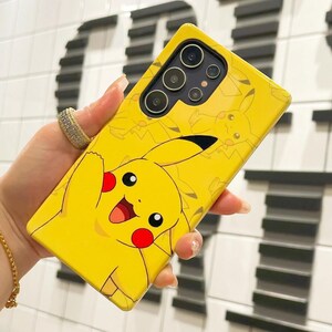 May include: A yellow phone case with a cartoon Pikachu design. The case has a camera cutout with multiple lenses.