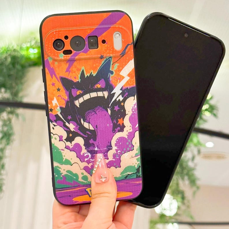 May include: A colorful phone case featuring a cartoon monster with a long purple tongue, set against an orange and purple background. The case has a black border and a camera cutout.