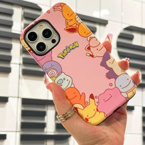 May include: A pink iPhone case with a white border and a Pokemon design. The case features a variety of Pokemon characters, including Pikachu, Jigglypuff, and Squirtle. The case also has the word "Pokemon" written in white letters.