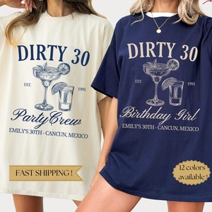 May include: Two t-shirts with a graphic design of a margarita and a shot glass. The text on the shirts reads "Dirty 30" and "Est. 1995". One shirt is natural colored with navy blue text and the other is navy blue with natural colored text. The text on the natural colored shirt reads "Party Crew" and the text on the navy blue shirt reads "Birthday Girl".
