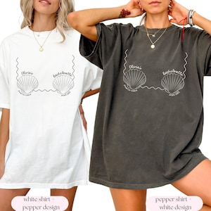 May include: Two oversized t-shirts with a white design of seashells and the text "Olivia's Bachelorette Punta Cana June 2023". One shirt is white and the other is a dark gray color.