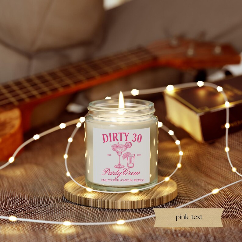 May include: A white candle in a glass jar with a pink label that says "Dirty 30 Party Crew Emily's 30th Cancun, Mexico". The label also features a pink illustration of a margarita glass with a lime wedge and a shot glass.