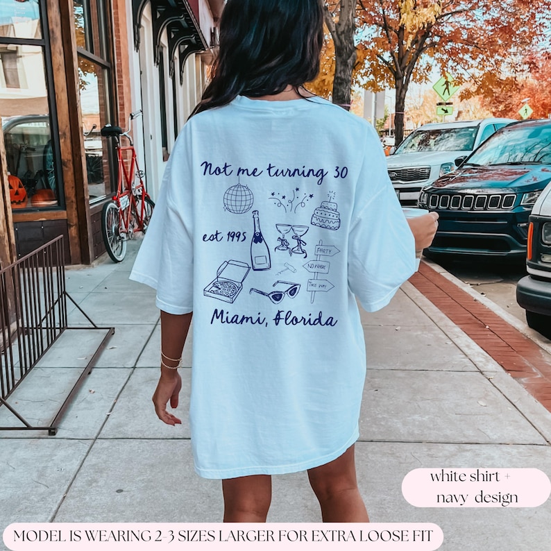 May include: White t-shirt with a navy blue design that says "Not me turning 30 est 1995 Miami, Florida" with various party-themed illustrations.