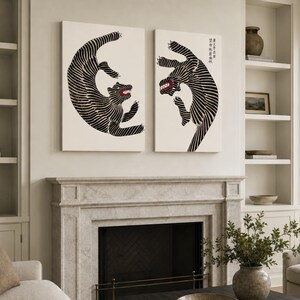 May include: Two rectangular wall art prints featuring stylized black and white tigers with red mouths. The tigers are depicted in dynamic, leaping poses with striped patterns. The right print includes vertical Japanese text in the upper corner.