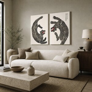 May include: Two rectangular wall art prints featuring black and white striped tigers in dynamic poses against a cream background. The tiger on the right includes vertical black Japanese text in the upper right corner. Both tigers have red mouths.