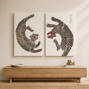 May include: Two rectangular wall canvases featuring black and white striped tiger illustrations with red mouths. The left tiger is curved, while the right tiger is leaping and includes vertical black Chinese characters in the upper right corner.