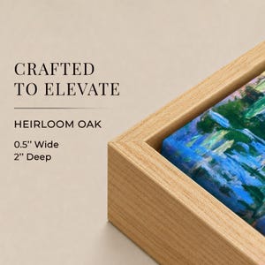 May include: A light-toned oak wood floating frame containing a canvas painting with blue and green brushstrokes. The text reads: CRAFTED TO ELEVATE, HEIRLOOM OAK, 0.5" Wide, 2" Deep. The frame has a clean, angular profile with a visible natural wood grain.