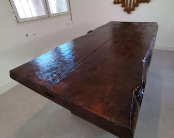 Puede incluir: Una mesa grande de madera marrón oscura con un diseño de borde vivo. La mesa está hecha de dos gruesas losas de madera que se han unido. La mesa tiene un aspecto natural y rústico y sería una gran adición a cualquier comedor o sala de estar.
