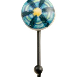 Peut inclure: Un crochet en métal noir avec un bouton rond en céramique. Le bouton présente un motif floral bleu, vert et jaune.