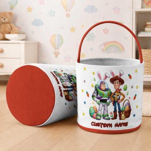 May include: White Easter basket with a red trim and handle, featuring Buzz Lightyear and Woody in bunny ears. A matching cylindrical container is next to the basket. The text "CUSTOM NAME" is printed on the basket.
