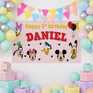 May include: A pink birthday banner with the text "Happy 5th birthday DANIEL" and cartoon character faces. The banner is decorated with balloons and a colorful pennant banner. There are wrapped gifts and balloons in the foreground.