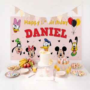May include: A pink birthday party backdrop with Disney characters, the name "DANIEL", and the text "Happy 5th Birthday". The table is set with a cake, cupcakes, cookies, fruit, and juice.