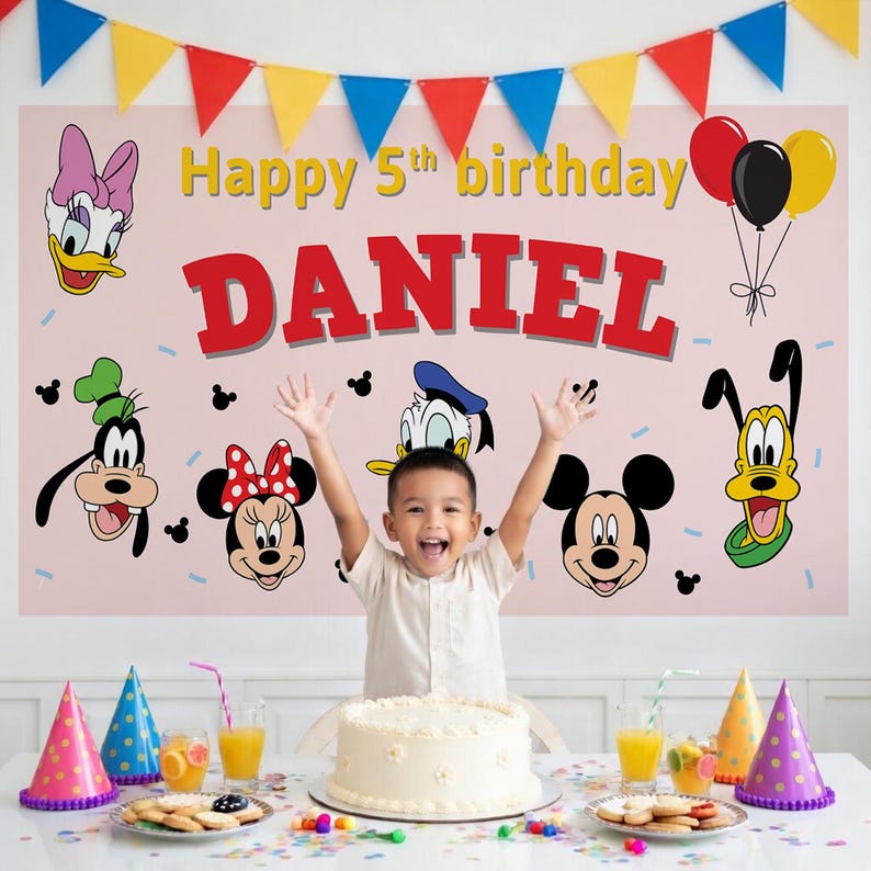 May include: A child celebrates their 5th birthday in front of a pink banner with the name "DANIEL" in red letters. The banner features cartoon characters and the text "Happy 5th birthday". A cake, party hats, and balloons are also visible.