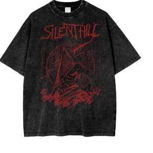 May include: Black t-shirt featuring a red graphic print of a character from the video game Silent Hill. The character is wearing a pyramid-shaped helmet and holding a large knife. The text "Silent Hill" is printed in red above the character.