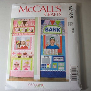 May include: A sewing pattern for a play kitchen set. The pattern includes instructions for making a cupcake shop and a bank. The pattern is from McCall's Crafts and is size OSZ.