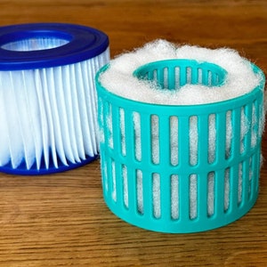 May include: Two round filter cartridges for a hot tub or spa. One is blue and white and the other is green and white. A pile of white cotton balls is to the right.