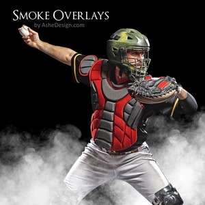 May include: A baseball catcher wearing a black and red chest protector, a green helmet with a face mask, and a white uniform, is catching a ball. The catcher is standing in a cloud of white smoke against a black background.