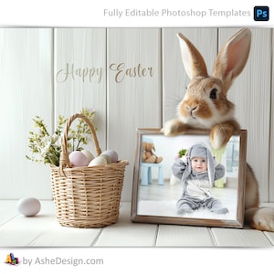 May include: A white wooden background with a brown bunny rabbit holding a picture frame. The frame contains a photo of a baby wearing a grey bunny costume. A wicker basket with pastel coloured Easter eggs and white flowers is in the foreground. The text "Happy Easter" is written in cursive on the background.