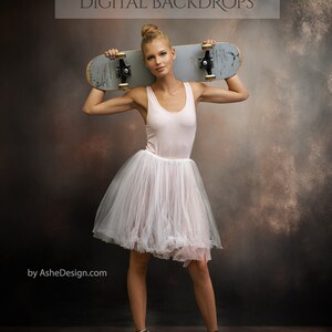 May include: A woman wearing a white tutu and black sneakers holds a skateboard over her shoulder. The background is a dark brown and gray textured backdrop.