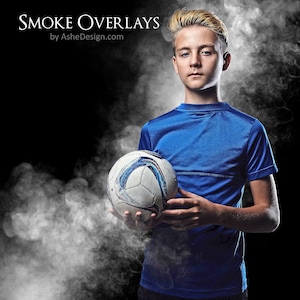 May include: A young person wearing a blue jersey holds a white and black soccer ball in front of a smoky background.