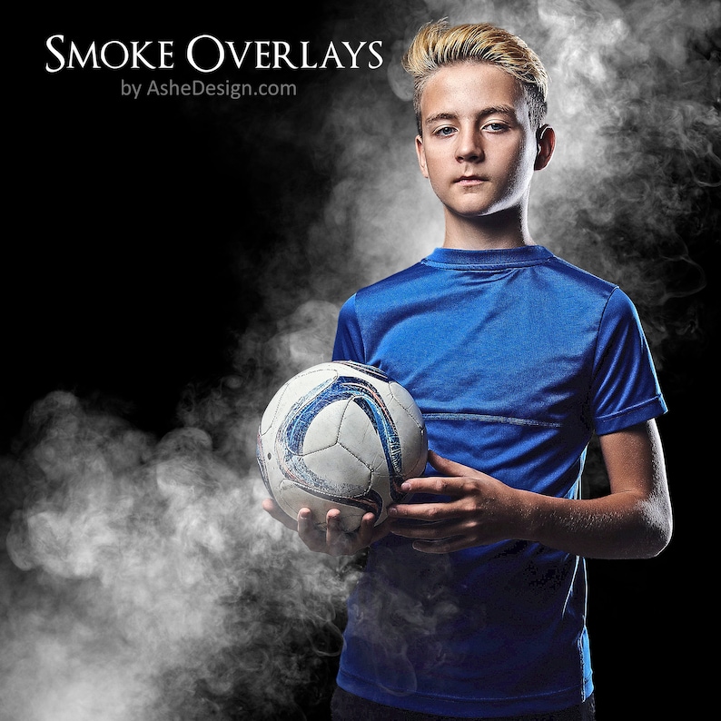 May include: A young person wearing a blue jersey holds a white and black soccer ball in front of a smoky background.