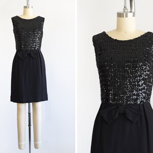A vintage late 50s early 60s black dress that has a black sequin bodice, a bow at the waist, and a pencil skirt. The dress is modeled on a dress form